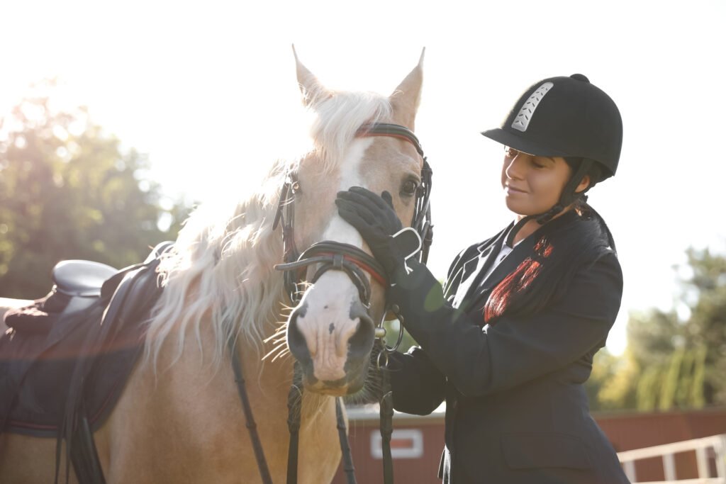 A woman in equestrian attire gently handling her horse, illustrating planning for a horse’s future care through a will or horse-care trust.